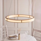Endon Bevley brushed gold LED ring pendant with ribbed frosted acrylic diffuser, suspended on clear cables above a dining table in a panelled room.