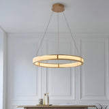 Endon Bevley brushed gold LED ring pendant with ribbed frosted acrylic diffuser, suspended from clear cables above a console in a panelled room.