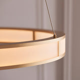 Close-up of Endon Bevley Ring Pendant in brushed gold, showing the ribbed frosted acrylic diffuser and clear suspension cable against a neutral wall.