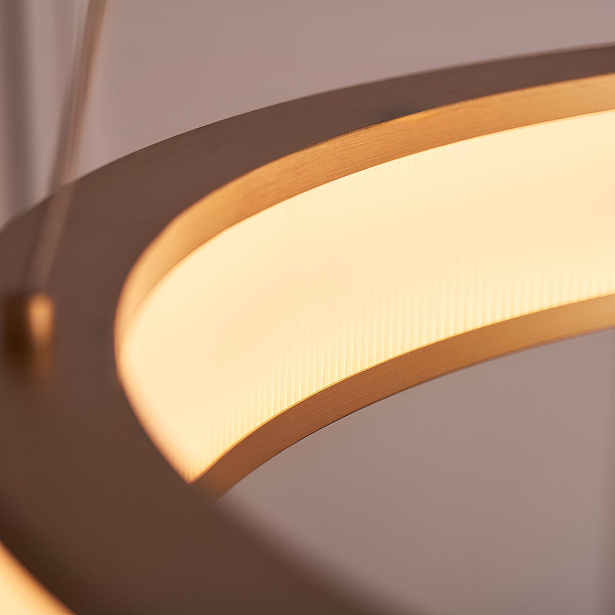 Close-up of the Endon Bevley ring pendant showing the brushed gold hoop and ribbed frosted acrylic diffuser glowing with warm white light.