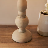 Endon Brenhurst table lamp base close-up showing hand-turned natural wood with rounded and tapered sections on a wooden surface beside a ceramic planter.