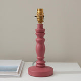 Endon Aldworth turned wood spindle table lamp in satin pink with a brass B22 switched lampholder, shown on a white surface beside a book.
