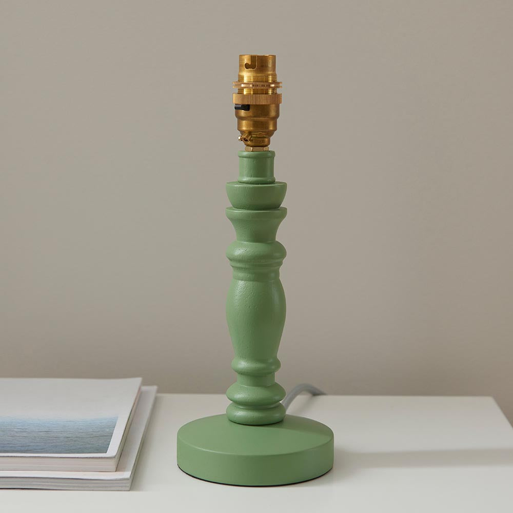 Aldworth Table Lamp base in sage green turned wood with brass B22 switched lampholder, round base, on a light surface against a neutral wall.