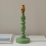 Aldworth Table Lamp base in sage green turned wood with brass B22 switched lampholder, round base, on a light surface against a neutral wall.