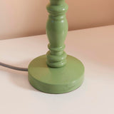 Aldworth Table Lamp base close-up, turned solid wood spindle in green satin finish with grey braided flex, shown on a light surface.