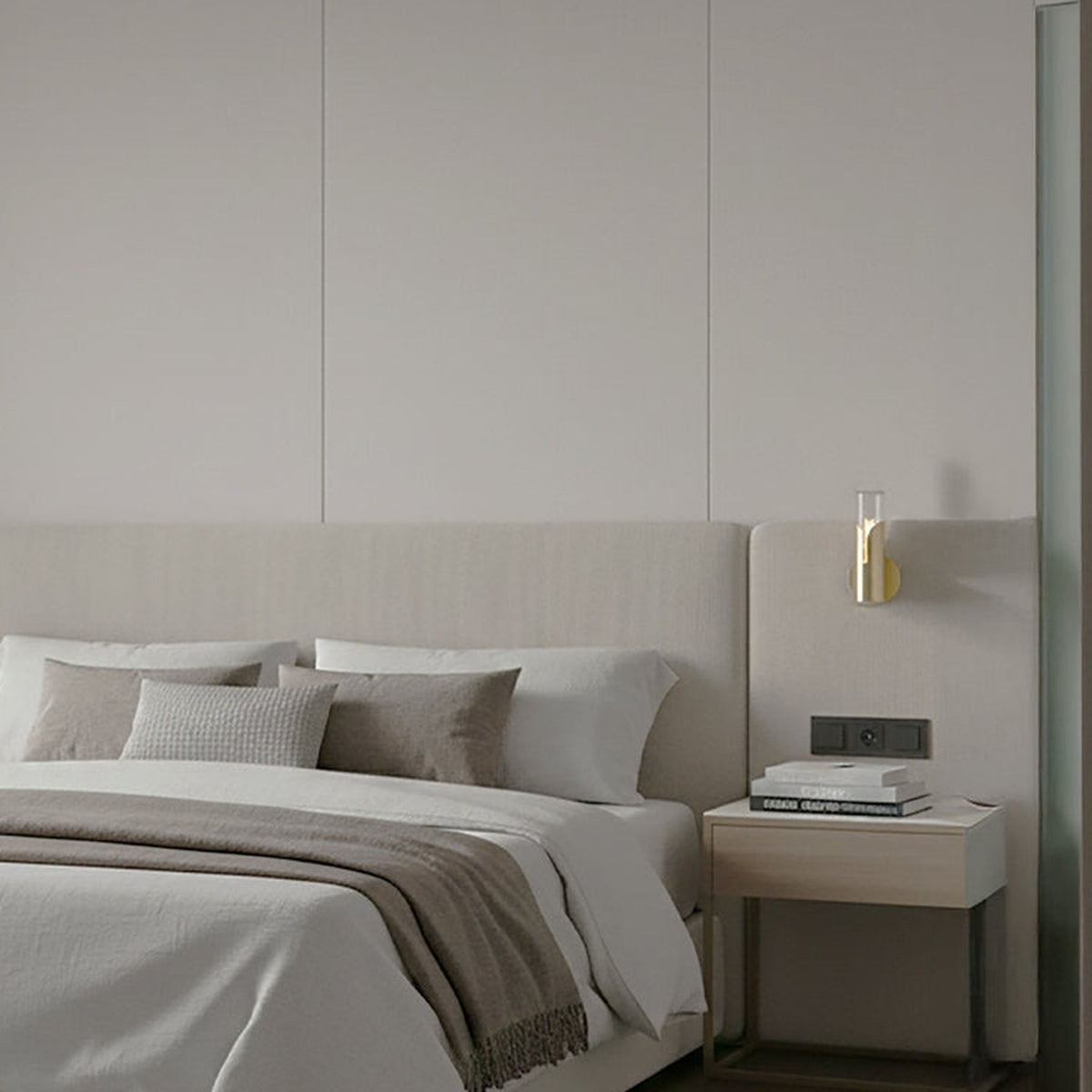 Bisel Cylinder Ribbed Glass Wall Light in gold mounted above a bedside table, with ribbed glass cylinder and curved metal sleeve, shown in a neutral-toned bedroom setting.