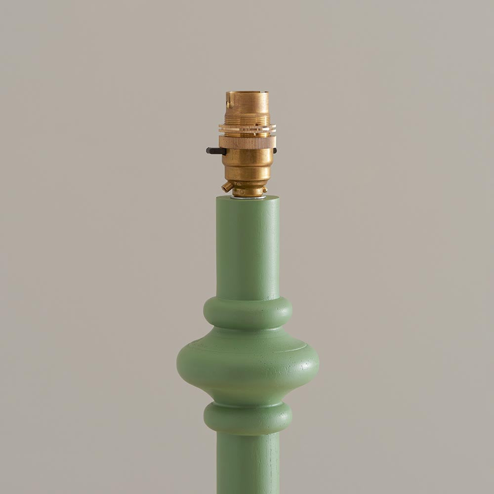 Close-up of the Endon Bevbury Floor Lamp showing the Cotswold green turned wood spindle base and switched brass B22 lamp holder against a neutral background.