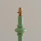 Close-up of the Endon Bevbury Floor Lamp showing the Cotswold green turned wood spindle base and switched brass B22 lamp holder against a neutral background.