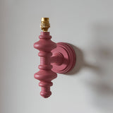 Endon Bevbury wall light with pink clay turned wooden spindle and brass B22 lamp holder, shown shadeless on a plain white wall.