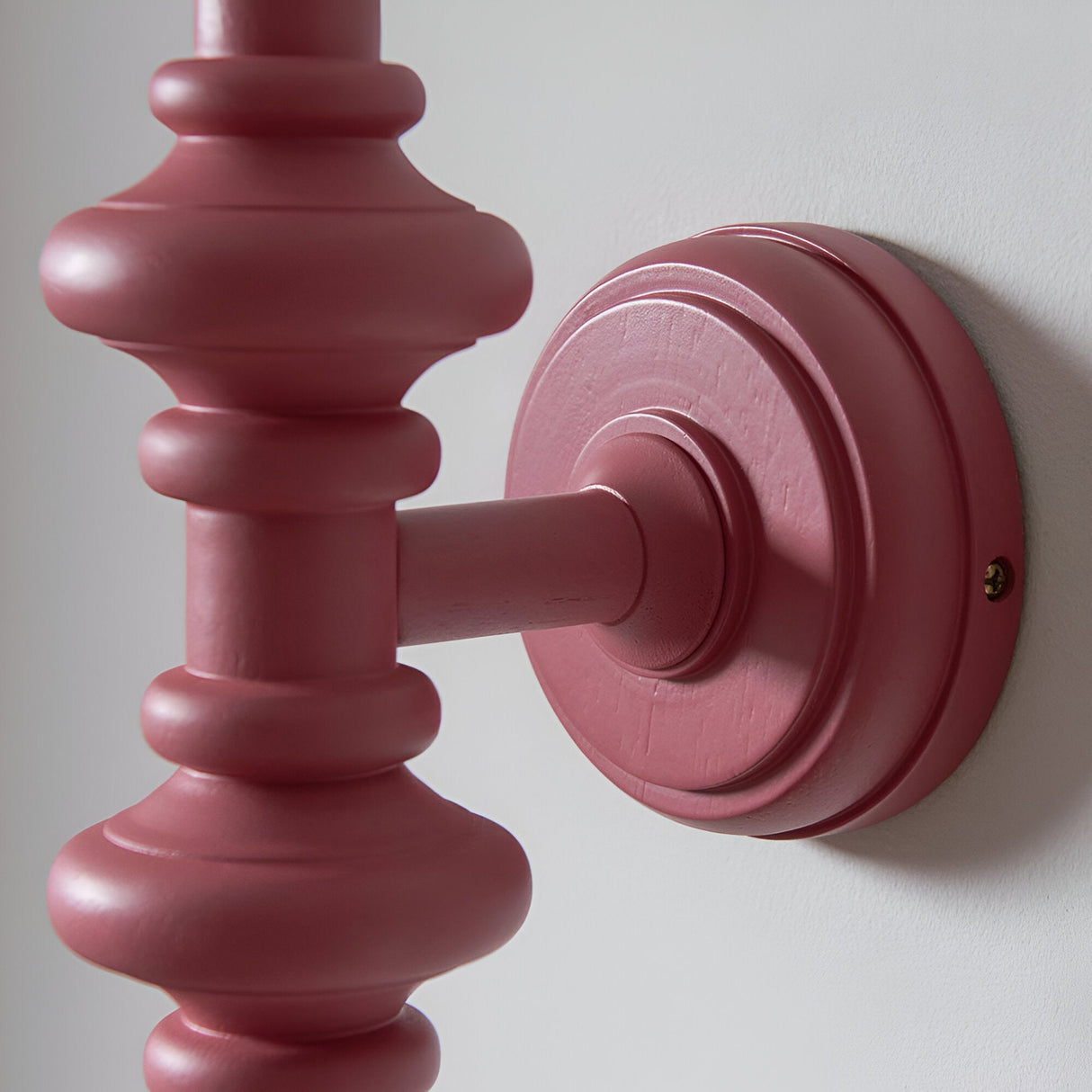 Close-up of Endon Bevbury wall light showing the turned wooden spindle and circular wall plate in satin pink clay finish against a white wall.