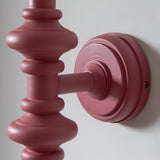 Close-up of Endon Bevbury wall light showing the turned wooden spindle and circular wall plate in satin pink clay finish against a white wall.