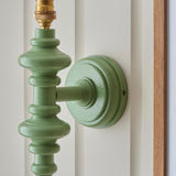Endon Bevbury wall light close-up showing the Cotswold green turned wooden spindle and brass B22 lamp holder mounted on a panelled wall.