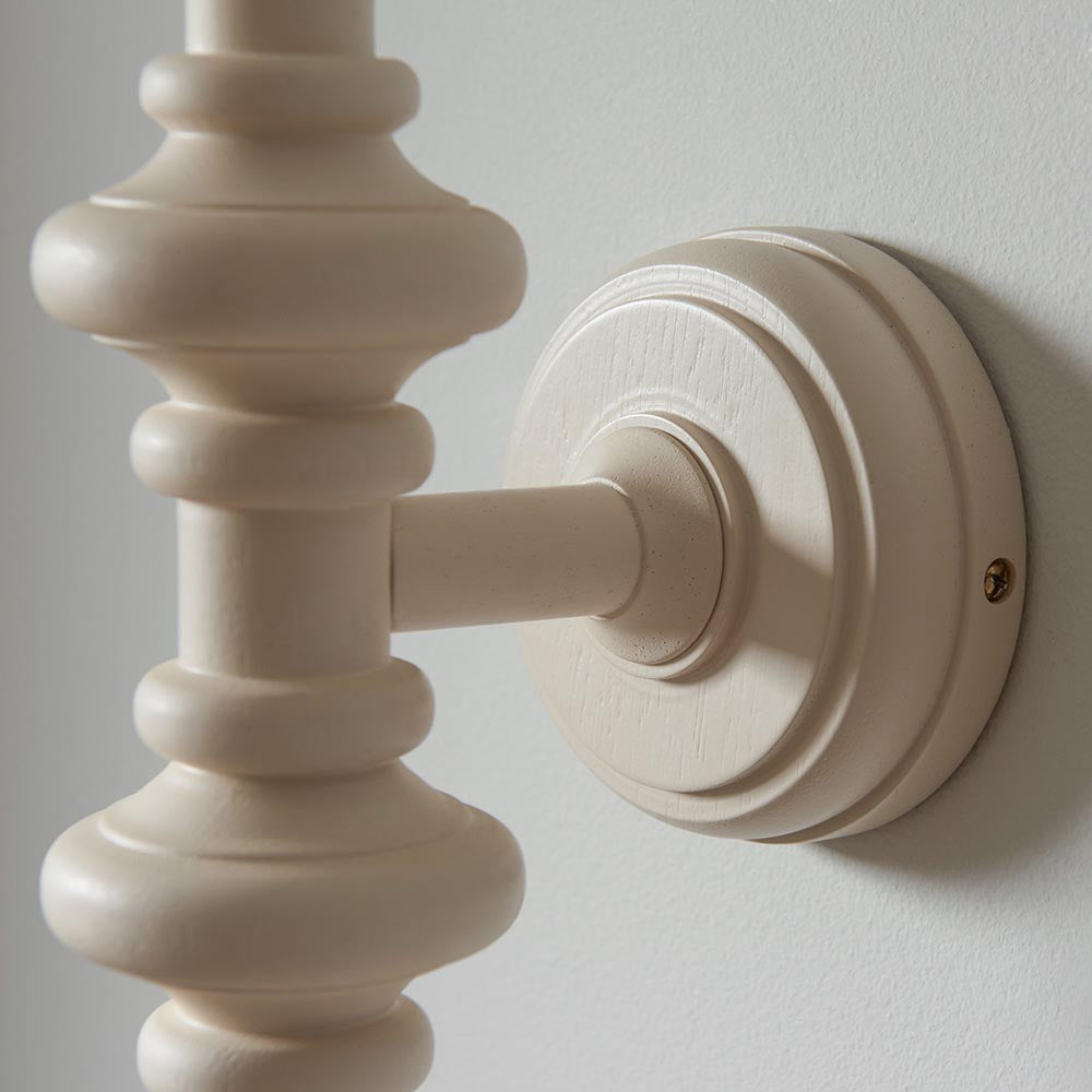 Close-up of Endon Bevbury wall light in almond white, showing the turned wooden spindle and round backplate mounted on a pale wall.