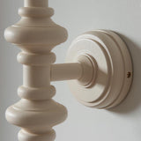Close-up of Endon Bevbury wall light in almond white, showing the turned wooden spindle and round backplate mounted on a pale wall.