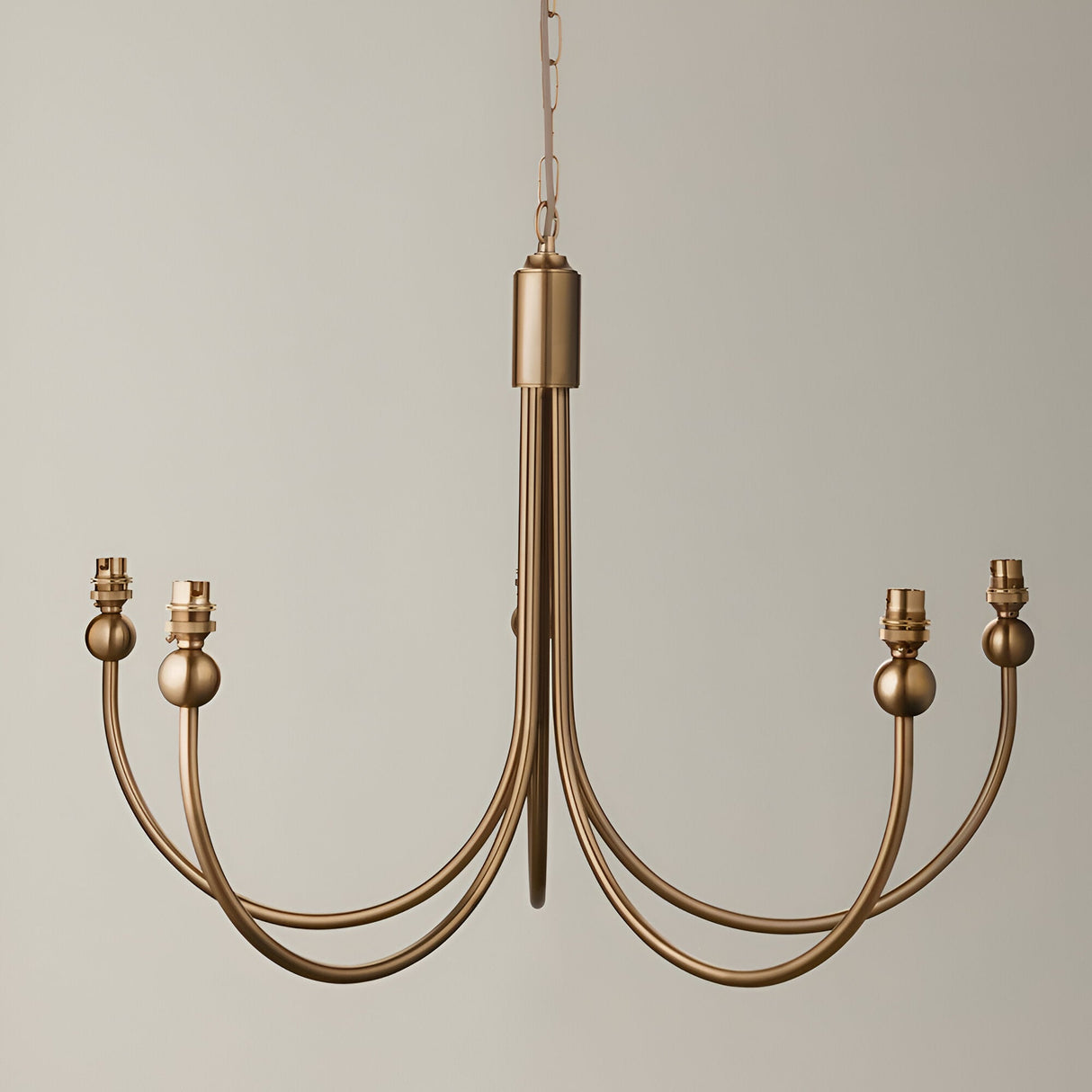 Endon Cliffleigh 5 light chandelier in brushed aged brass with curved J shaped arms and B22 lamp holders, hung from a chain against a neutral background.