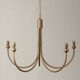 Endon Cliffleigh 5 light chandelier in brushed aged brass with curved J shaped arms and B22 lamp holders, hung from a chain against a neutral background.