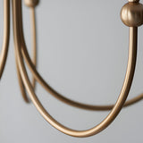 Close-up of the Endon Cliffleigh 5 Light Chandelier showing brushed aged brass J-shaped curved arms and ball detailing against a light grey background.