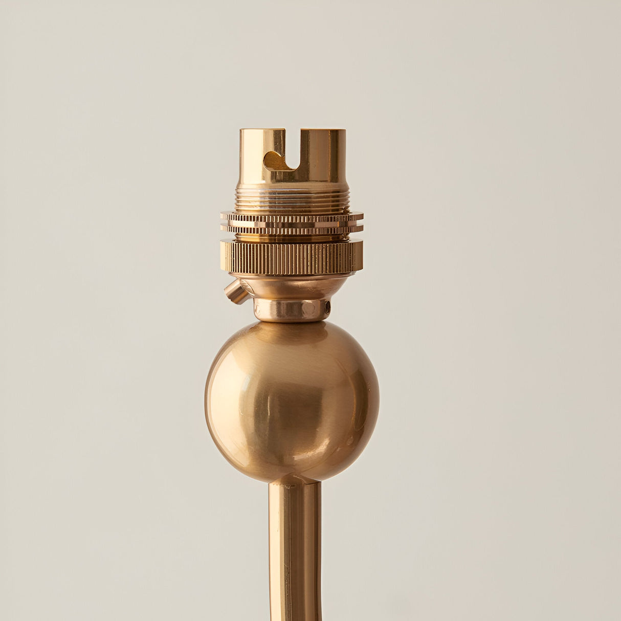 Close-up of the Endon Cliffleigh chandelier's brushed aged brass B22 lamp holder and spherical detail on the central stem, against a light background.