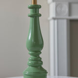 Endon Carlworth table lamp base close-up showing the turned spindle shape in high gloss green resin with a brass fitting above.