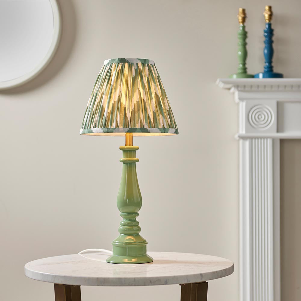 Endon Carlworth table lamp with a gloss green turned spindle resin base and brass holder, topped with a pleated green ikat shade, on a marble side table.