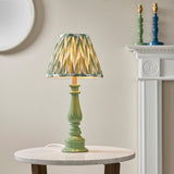 Endon Carlworth table lamp with a gloss green turned spindle resin base and brass holder, topped with a pleated green ikat shade, on a marble side table.