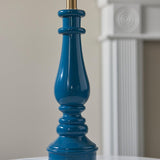 Endon Carlworth table lamp base in high gloss Marlin Blue resin, shaped like a turned spindle with brass fitting, shown beside a white fluted column.