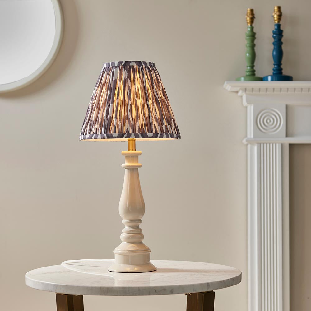 Carlworth Table Lamp in white resin with a turned spindle base and brass fitting, shown with a patterned shade on a marble side table.