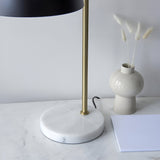 Endon Ashmont table lamp detail showing the white and grey marble base, antique brass stem and matt black shade beside a ceramic vase.