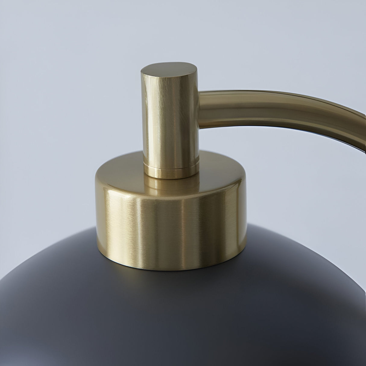 Close-up of the Endon Ashmont table lamp showing the antique brass stem curving into the matt black shade against a light background.
