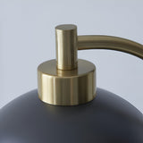 Close-up of the Endon Ashmont table lamp showing the antique brass stem curving into the matt black shade against a light background.