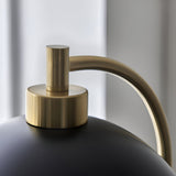 Close-up of the Endon Ashmont floor lamp showing the antique brass curved stem meeting the matt black shade.