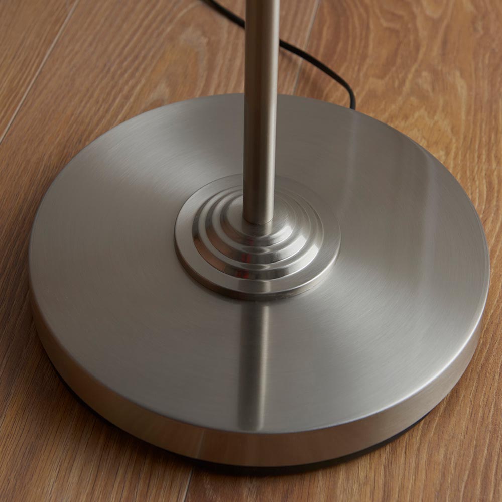 Close-up of the circular tiered base and slim stem of the Endon Brenley floor lamp in brushed chrome, shown on wood flooring.