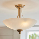 Carlton 3 Light Flush Ceiling Light in brushed aged brass, with a frosted glass bowl shade and three lamp fittings, shown illuminated near a room ceiling.