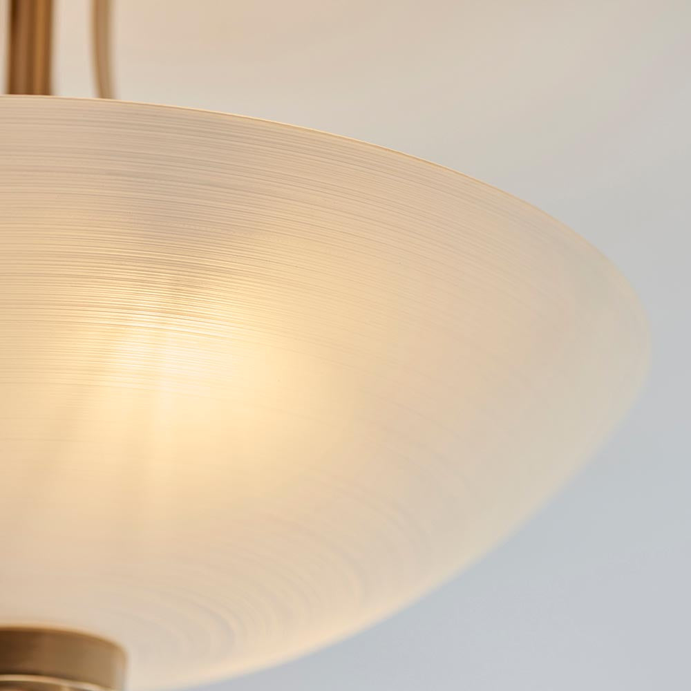 Close-up of the Carlton 3 Light Flush Ceiling Light with a textured white glass shade and brushed aged brass fitting, on a plain light background.
