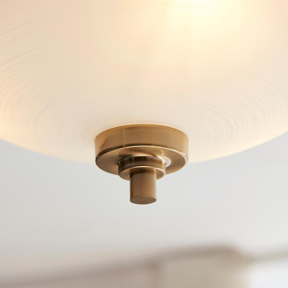 Close-up of the Carlton 3 Light Flush Ceiling Light in brushed aged brass, showing the frosted glass shade and brass mounting detail against a plain background.