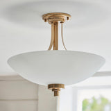 Carlton 3 Light Flush Ceiling Light in brushed aged brass, with a frosted glass bowl shade close to the ceiling, shown in a bright room.