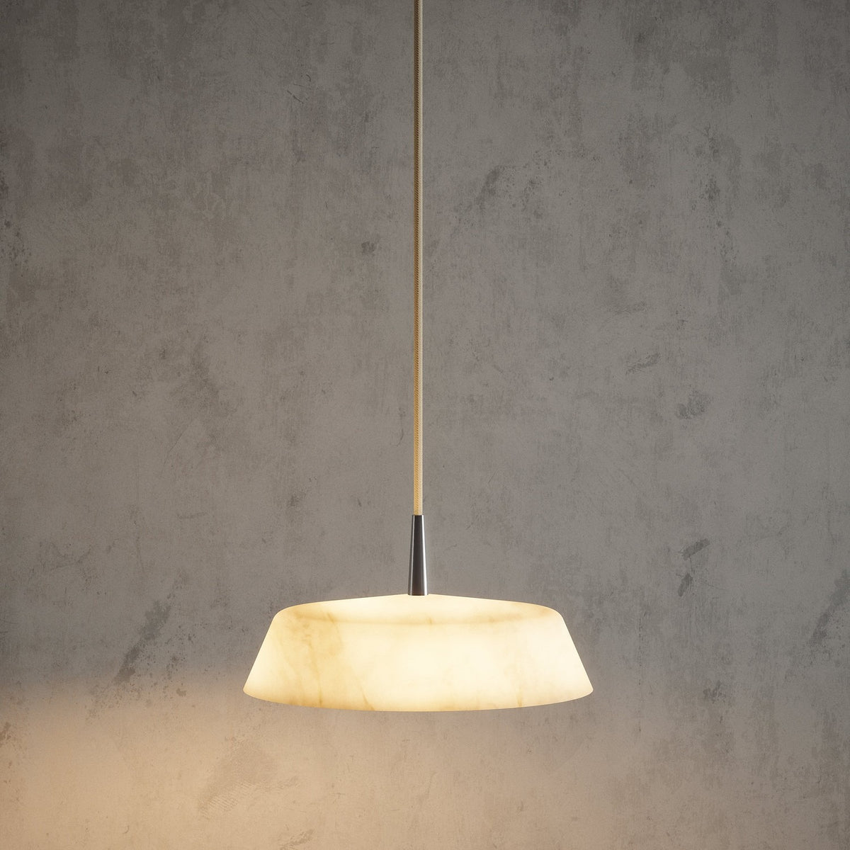 Bonn Alabaster Drum Pendant Light with a shallow, tapered veined alabaster shade on a slim metallic stem and cream textile cable, lit warm white against a grey background.
