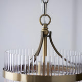 Close-up of Endon Beaumont pendant showing antique brass chain suspension, curved arms, and clear glass rods around the compact circular frame.
