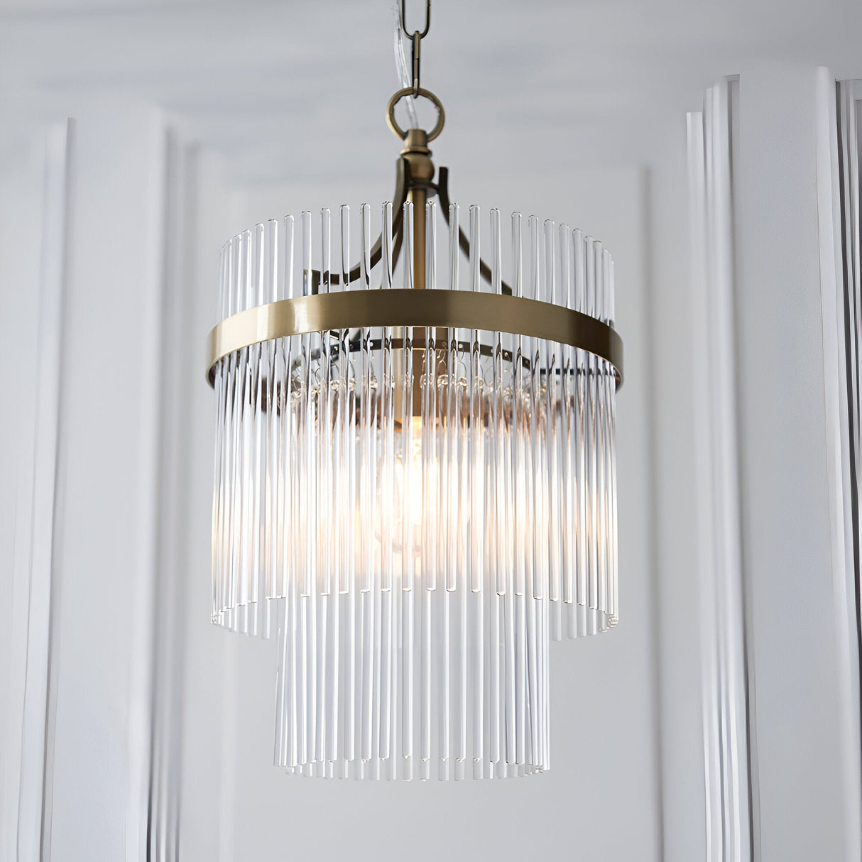 Endon Beaumont two-tier pendant light with clear glass rods and antique brass frame, suspended from a chain in a bright interior setting.