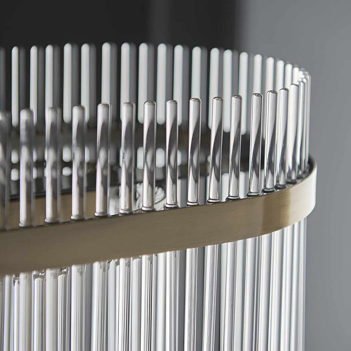Close-up of the Beaumont 4 Light Linear Pendant, showing clear glass rods lined along an antique brass bar for a decorative diffused glow.
