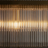 Close-up of the Beaumont 4 Light Linear Pendant, showing clear glass rods along an antique brass bar with warm glowing bulbs visible through the rows.