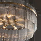 Close-up of Endon Beaumont 7 Light Pendant in antique brass, showing lit E14 lamps, tiered rings and clear glass rod fringing.