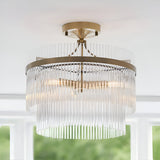 Endon Beaumont 3 light semi-flush ceiling light in brass with tiered clear glass rod fringes, mounted to a white ceiling near a bright window.