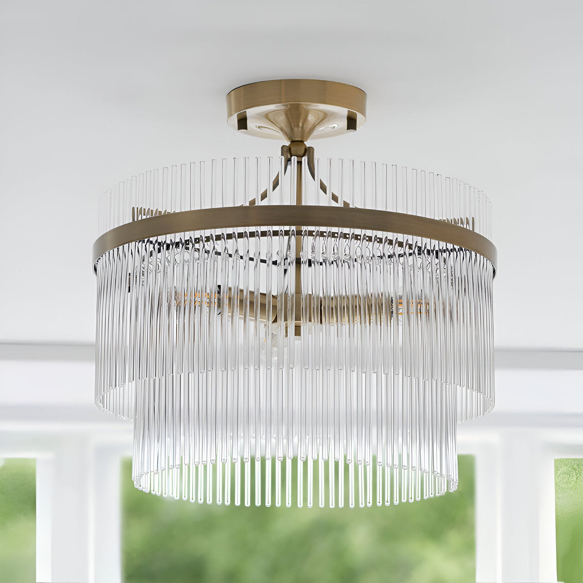 Endon Beaumont 3 light semi-flush ceiling light in brass with two tiered rings of clear glass rods, mounted to a white ceiling near a window.
