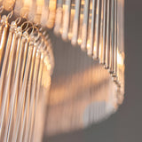 Close-up of the Beaumont 16 Light Chandelier in antique brass, showing tiered clear glass rods diffusing warm light against a grey background.