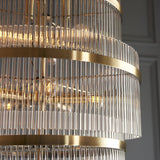 Close-up of Endon Beaumont 21 light chandelier in antique brass, showing tiered bands of clear glass rods and lit E14 bulbs within.