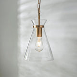 Endon Brenbury pendant light with a clear tapered glass shade, brushed brass fitting and exposed E27 filament bulb, hung against a soft neutral wall.