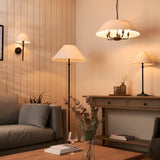 Endon Caldmere 5 light pendant with a wide natural linen shade and black metalwork, shown in a living room with matching wall, floor and table lamps.