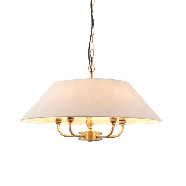 Caldmere 5 Light Pendant in brass, with a wide natural fabric drum shade and five arms, hung from a chain and black cable on a plain white background.