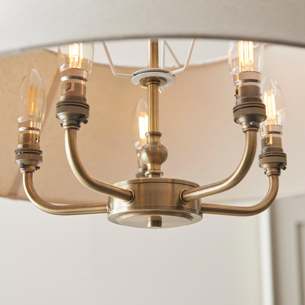 Caldmere 5 Light Pendant in brass, showing five candle bulbs on curved arms with a natural fabric shade above, close-up view.